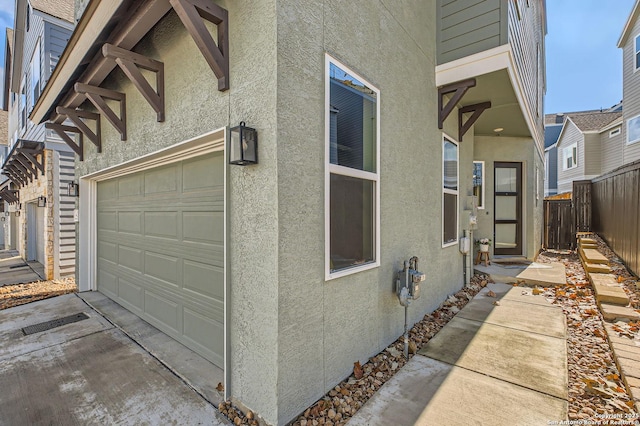 view of home's exterior featuring a garage, fence, and stucco siding