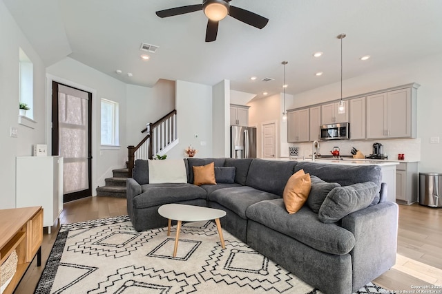 living room featuring light wood finished floors, visible vents, ceiling fan, stairway, and recessed lighting