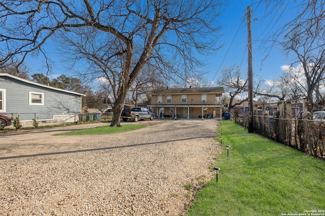 view of front of house with driveway, a front yard, and fence