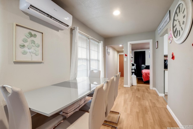 dining space with light wood finished floors, a wall mounted AC, recessed lighting, and baseboards