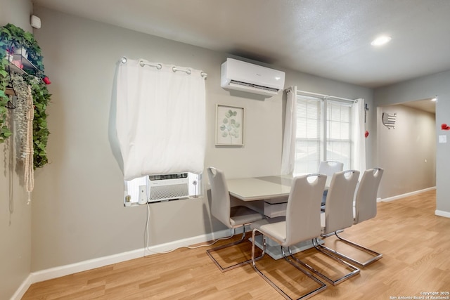 dining room featuring light wood-type flooring, baseboards, and a wall mounted AC