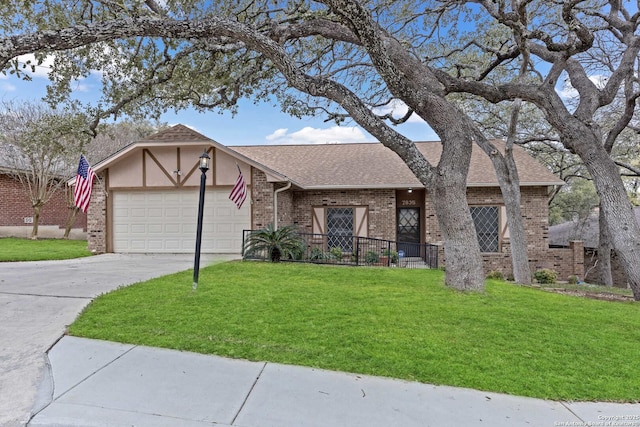 view of front of home featuring brick siding, roof with shingles, an attached garage, a front yard, and driveway