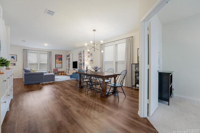 dining room featuring baseboards, wood finished floors, visible vents, and an inviting chandelier