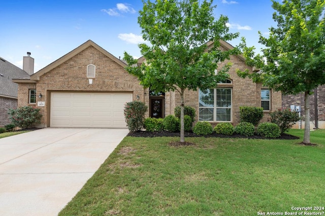 view of front of home featuring an attached garage, concrete driveway, brick siding, and a front yard