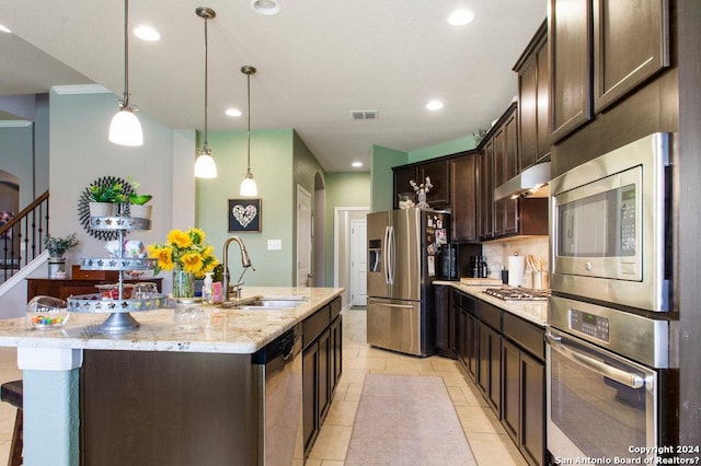 kitchen with visible vents, an island with sink, appliances with stainless steel finishes, light stone counters, and under cabinet range hood