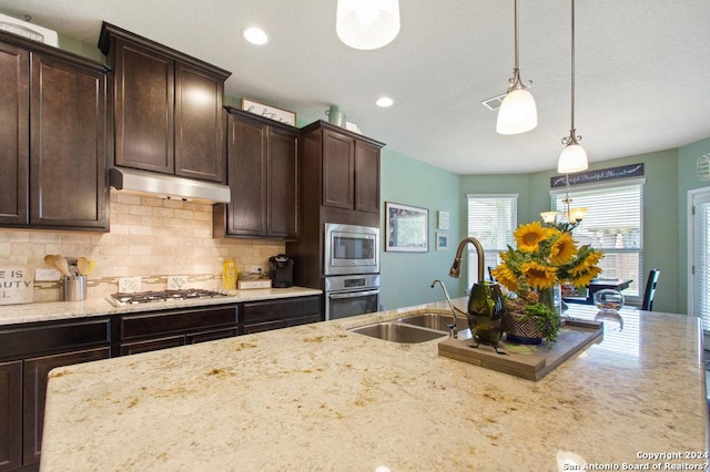 kitchen featuring stainless steel appliances, decorative light fixtures, dark brown cabinetry, and under cabinet range hood