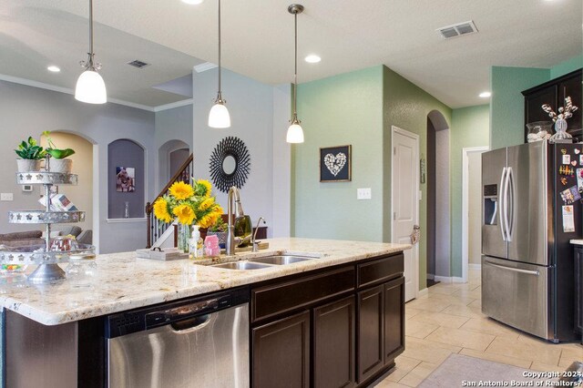 kitchen with appliances with stainless steel finishes, arched walkways, a sink, and pendant lighting