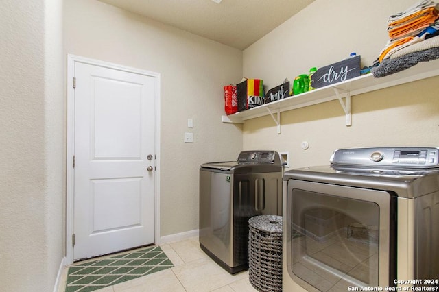 clothes washing area featuring washer and dryer, laundry area, light tile patterned flooring, and baseboards