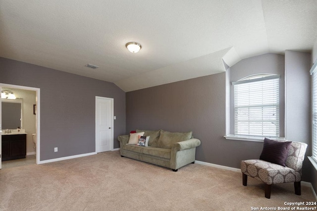 sitting room featuring lofted ceiling, visible vents, baseboards, and light colored carpet