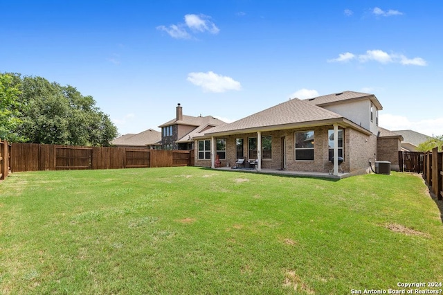 rear view of house featuring a fenced backyard, a lawn, brick siding, and central AC unit