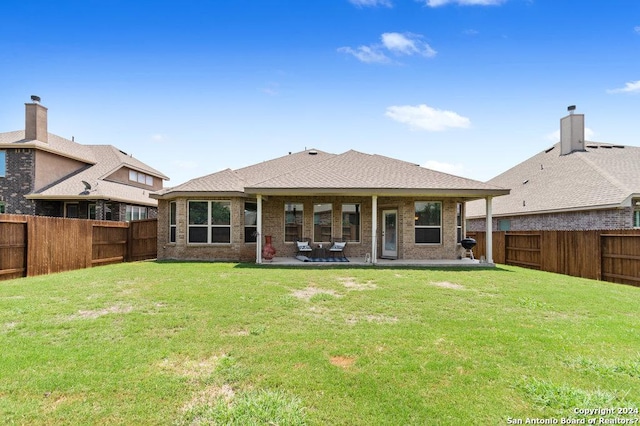 back of house featuring a patio, brick siding, a lawn, and a fenced backyard