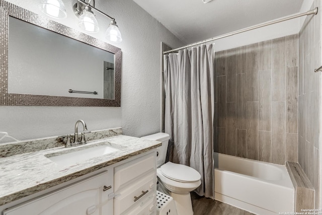 bathroom with a textured wall, toilet, wood finished floors, vanity, and shower / bath combo