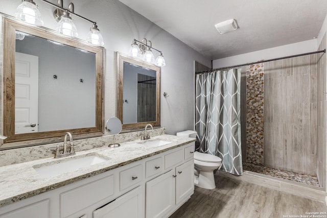 bathroom with toilet, a shower with shower curtain, a sink, and wood finished floors