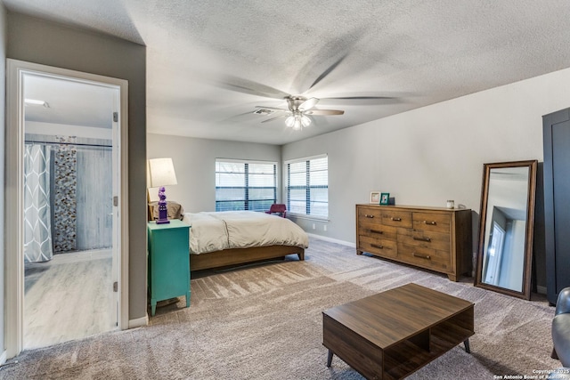 bedroom featuring light carpet, baseboards, a ceiling fan, and a textured ceiling