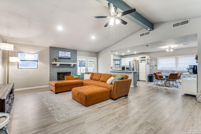 living room featuring a wealth of natural light, visible vents, a fireplace, and light wood-style flooring