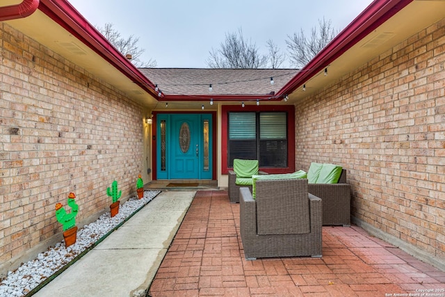 doorway to property with a shingled roof and brick siding