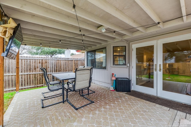 view of patio with french doors, outdoor dining area, and fence