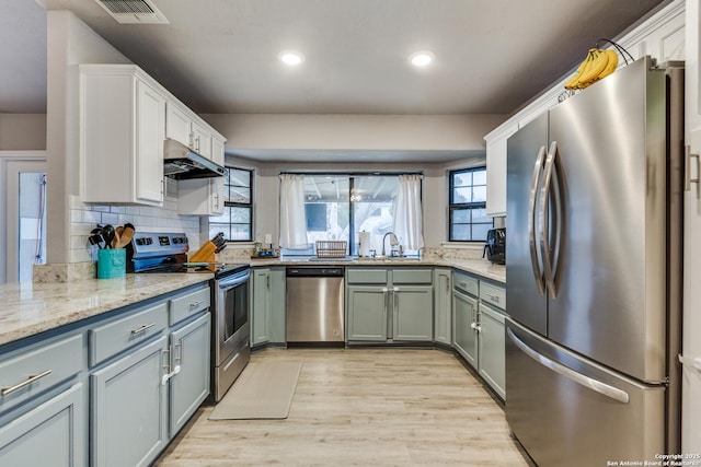 kitchen with under cabinet range hood, plenty of natural light, appliances with stainless steel finishes, and light wood finished floors