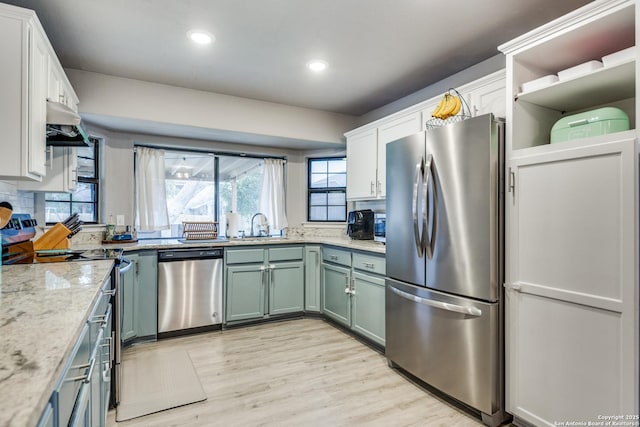 kitchen with stainless steel appliances, light wood-style floors, white cabinetry, a sink, and recessed lighting