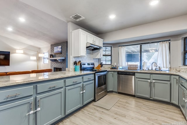 kitchen with visible vents, light wood-style floors, appliances with stainless steel finishes, under cabinet range hood, and a sink