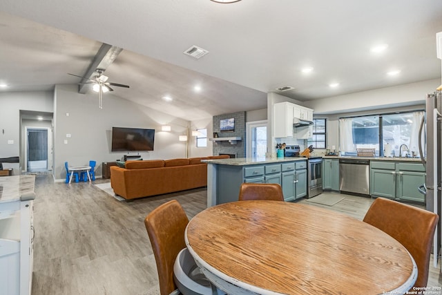 dining space featuring lofted ceiling with beams, light wood-type flooring, visible vents, and plenty of natural light