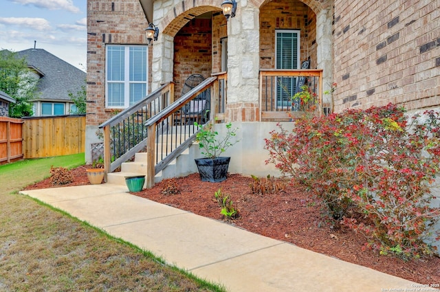 entrance to property with stone siding, fence, and brick siding