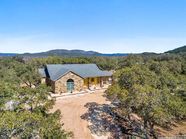 view of front of home featuring stone siding, a mountain view, and dirt driveway