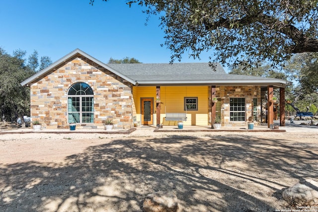 view of front of house with stone siding and roof with shingles