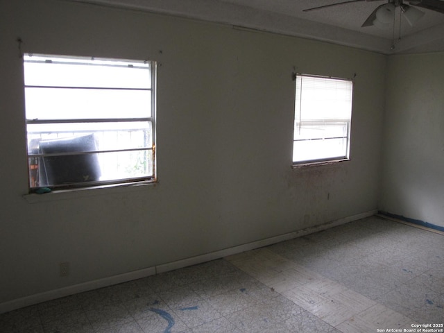 spare room featuring light floors, a wealth of natural light, and baseboards