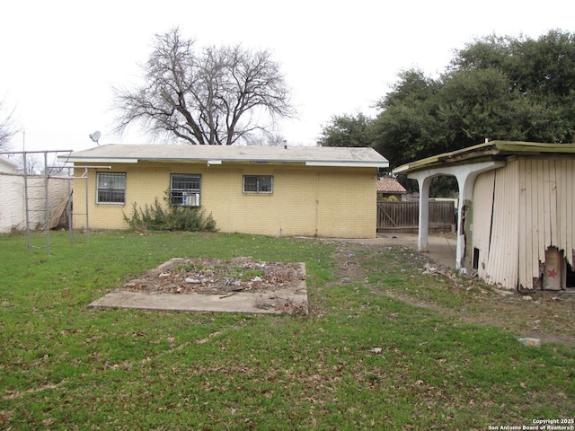 rear view of property featuring brick siding, a lawn, and fence