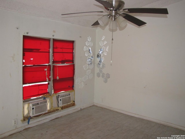 spare room featuring a ceiling fan, a textured ceiling, baseboards, and cooling unit