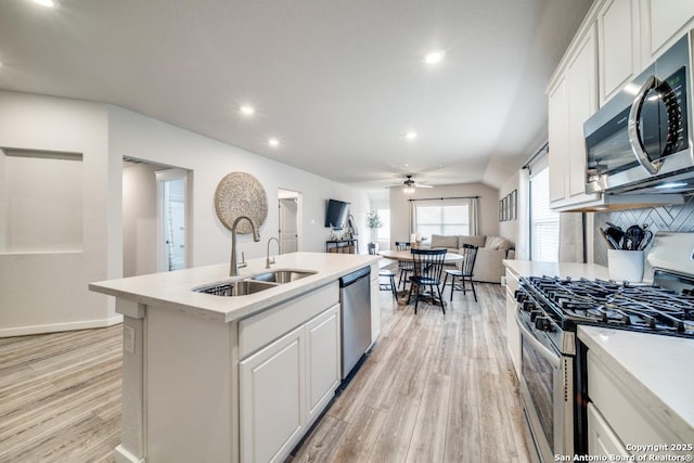 kitchen featuring white cabinets, open floor plan, a kitchen island with sink, stainless steel appliances, and light countertops