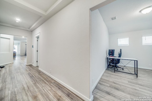 hall with light wood-type flooring, visible vents, and baseboards