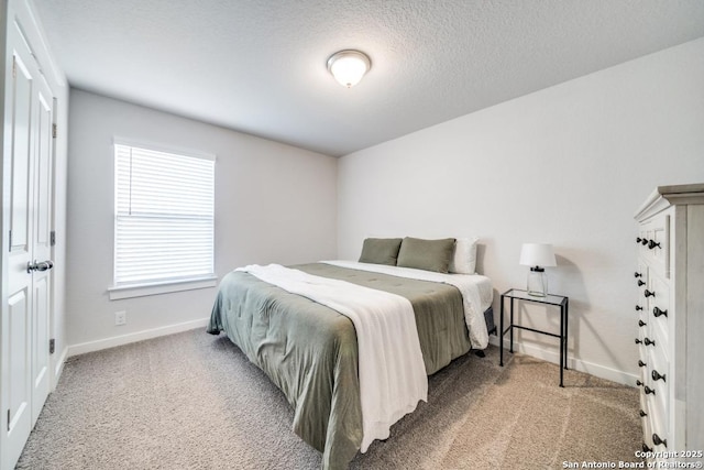 bedroom with light carpet, baseboards, and a textured ceiling