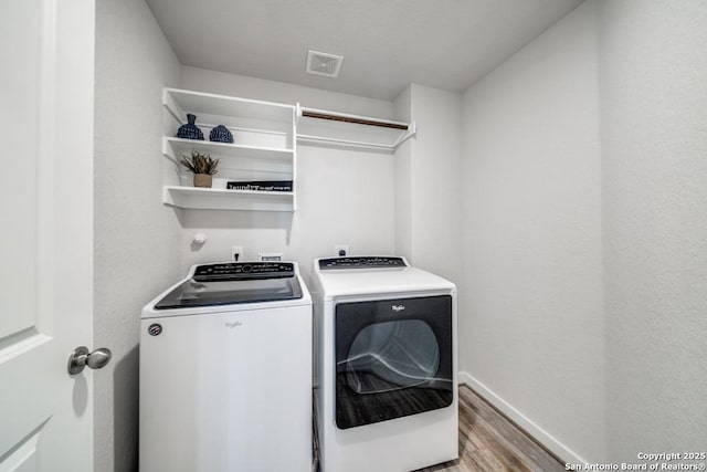 laundry area featuring light wood finished floors, visible vents, washing machine and dryer, laundry area, and baseboards