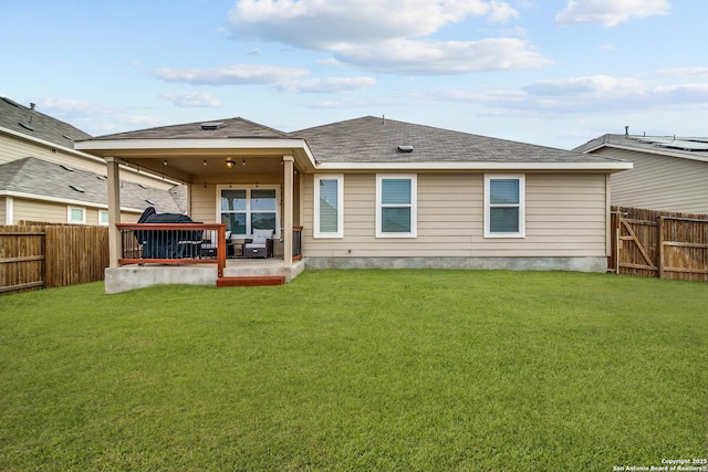 rear view of property with a fenced backyard, a shingled roof, and a yard