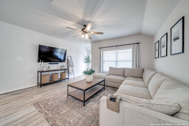 living room featuring lofted ceiling, visible vents, baseboards, a ceiling fan, and light wood-style floors