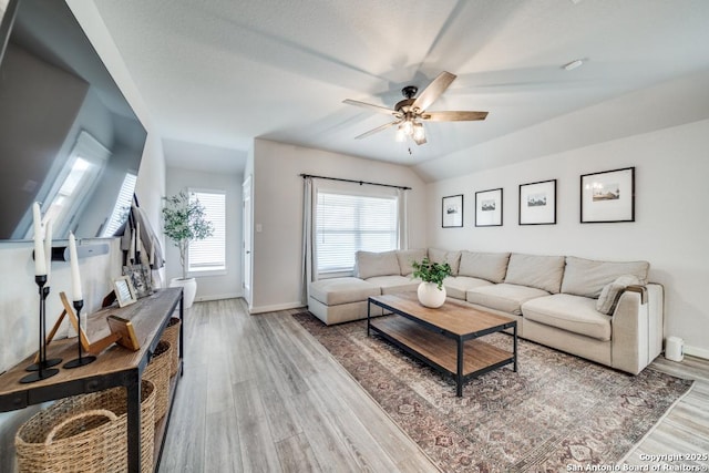 living area with lofted ceiling, ceiling fan, baseboards, and wood finished floors