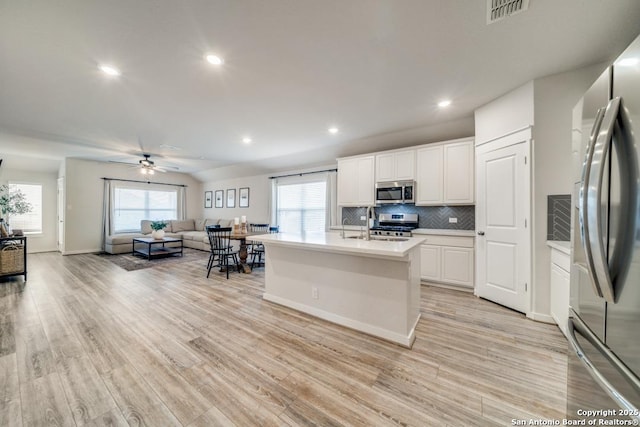 kitchen with visible vents, white cabinets, open floor plan, light countertops, and appliances with stainless steel finishes