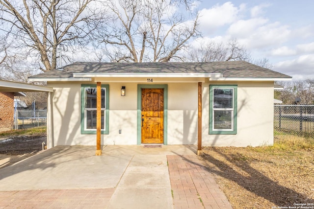 view of front of house with a shingled roof, fence, and stucco siding