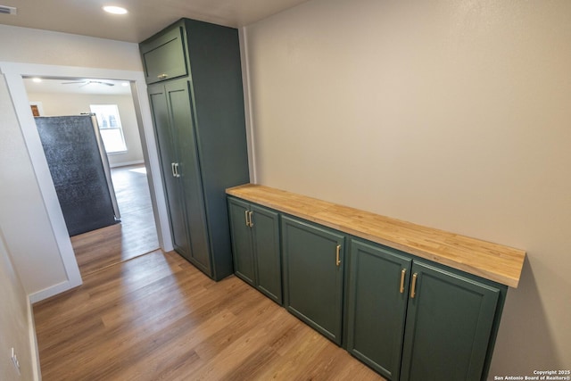 hall featuring light wood-style flooring, visible vents, baseboards, and recessed lighting