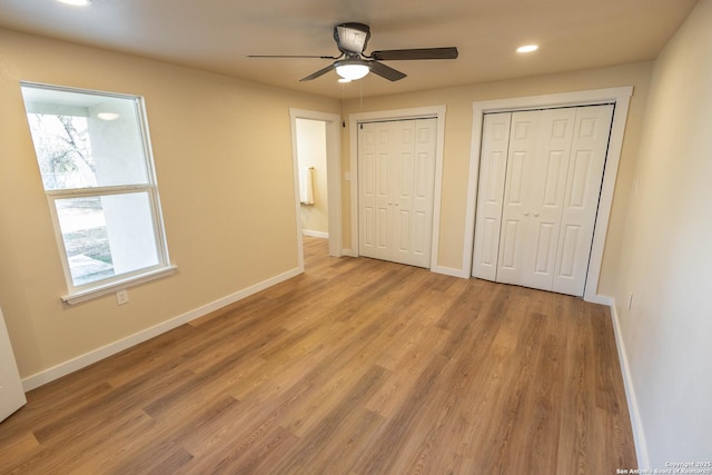 unfurnished bedroom featuring recessed lighting, light wood-type flooring, two closets, and baseboards