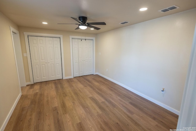 unfurnished bedroom featuring multiple closets, visible vents, and baseboards