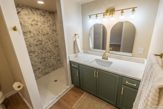 full bathroom featuring tiled shower, wood finished floors, and vanity