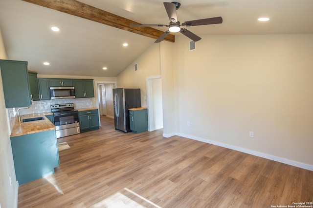 kitchen with tasteful backsplash, lofted ceiling with beams, stainless steel appliances, light wood-type flooring, and a sink