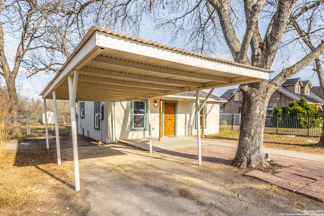 exterior space featuring a carport, fence, and stucco siding