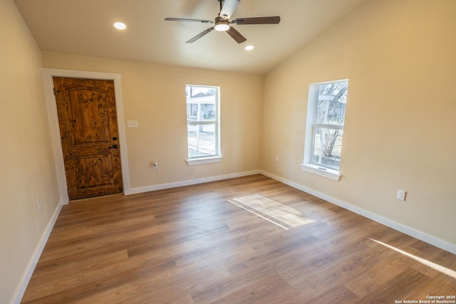 empty room featuring lofted ceiling, recessed lighting, wood finished floors, and a healthy amount of sunlight