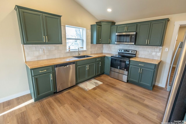 kitchen with appliances with stainless steel finishes, a sink, wood counters, and green cabinetry