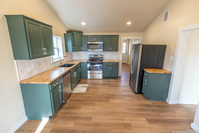 kitchen featuring stainless steel appliances, visible vents, wooden counters, vaulted ceiling, and a sink