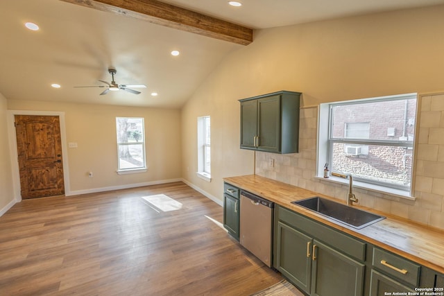 kitchen featuring green cabinetry, decorative backsplash, dishwasher, wooden counters, and a sink